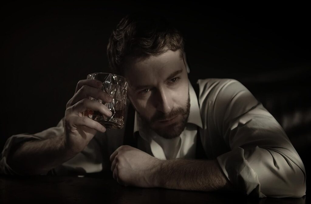 Treatment for Addiction and Dependence. Picture shows a man holding in the right hand a gals with alcohol