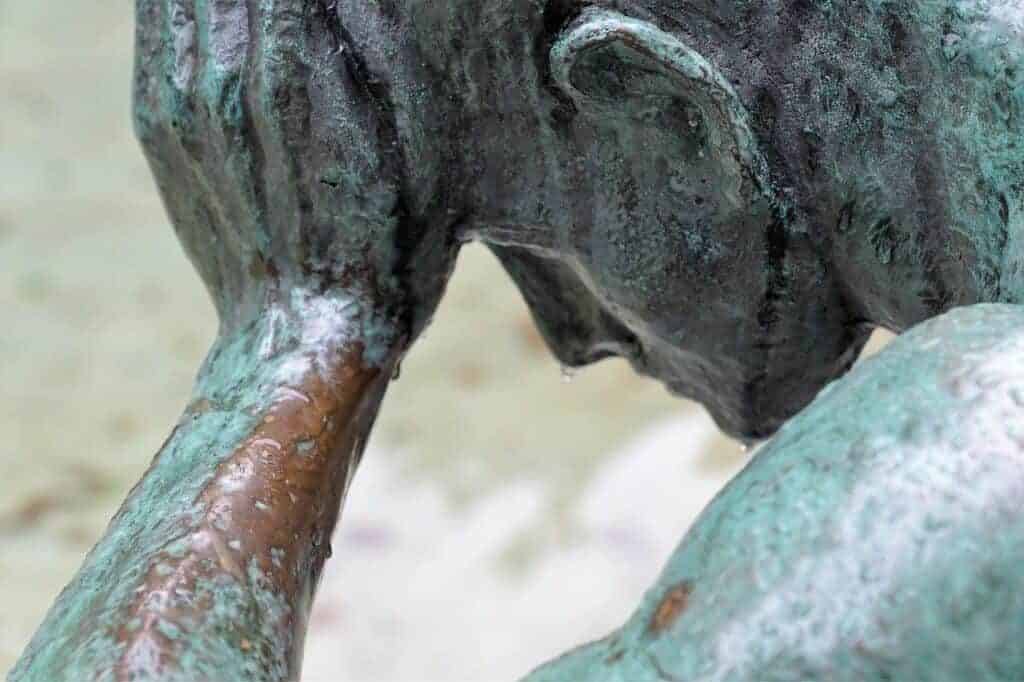 Chronic pain affects all aspects of life. A bronze statue showing a man holding his head in a sad, downward position. Counseling can help.