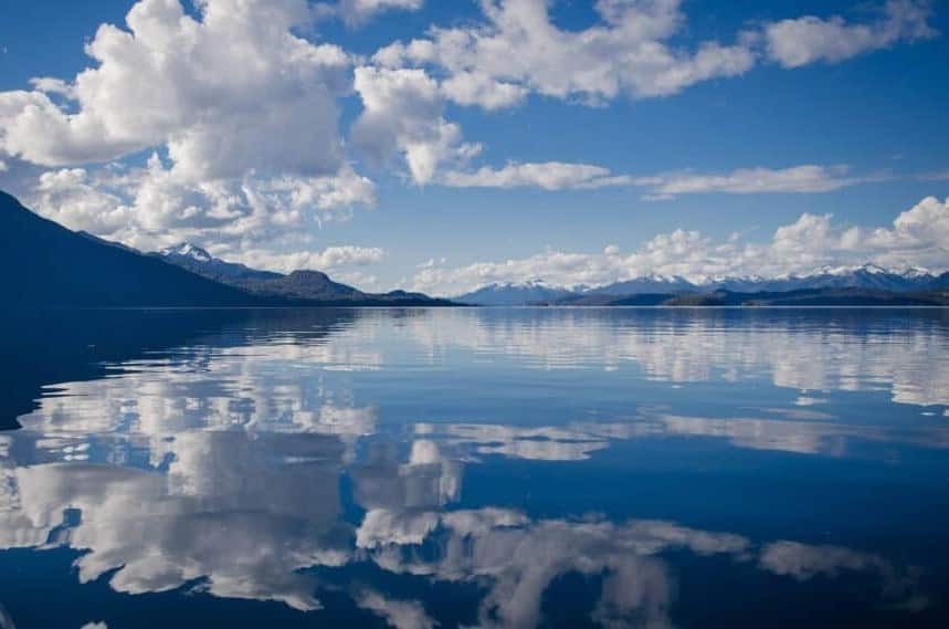 Hypnosis, Hypnotherapy, Dubai. Blue sky and clouds reflected in the water surrounded by mountains. What lies beneath the water represents the unconscious mind that hypnosis and clinical hypnotherapy focuses on.