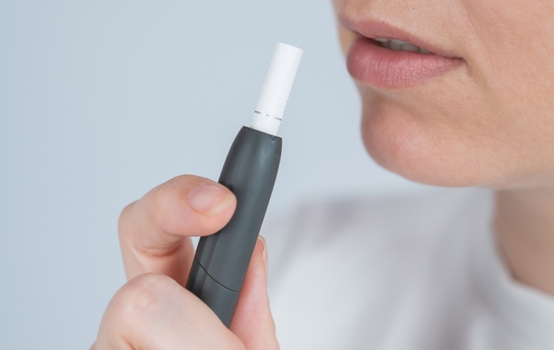 Developing tobacco addiction. The picture shows IQOS in the hand of a women